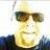 Pixelated static image of a person wearing dark sunglasses and a light-colored shirt against a bright background.