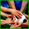 Multiple hands of varying skin tones overlap in a central stack, with arms extending from blue and green clothing, against a dark background.