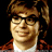Pixelated static image of a person with brown hair and glasses wearing a red jacket over a white shirt against black background.