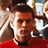 Pixelated close-up of a person with dark hair wearing red clothing, set against a blurred background with light and brown tones.