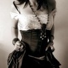 A grayscale image of a person wearing a white lace-trimmed top and dark corset-style garment with visible lacing.