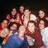 Group of people in various poses with red and blue clothing against dark background.