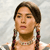Pixelated image of a person with dark braided hair, light skin, and a neutral expression against a light gray background.