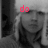 A grayscale image of a person with light-colored hair wearing a white head covering, overlaid with red text that changes