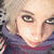 Pixelated close-up of a person with light hair and dark eyes, wearing a purple garment against a blurred background.