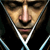 Pixelated close-up of a person's face with a silver chain necklace, dark clothing, and a neutral expression against a dark background.
