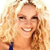 A pixelated close-up of a smiling person with light brown hair, wearing a dark blue top against a light background.