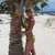 A four- shows a couple embracing on beach, woman in bikini inside circular frame, palm tree against blue sky, and woman in blue dress walking