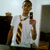 Pixelated static image of a person in white shirt holding multiple brown objects against light background.