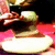 A pixelated figure with light skin and dark hair holds a black device against a red background, wearing a white circular garment.