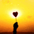Silhouette of a hand holding a heart-shaped object against a yellow-orange gradient background with bright light behind it.