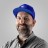Pixelated portrait of a person wearing a blue cap and dark clothing against a light background.