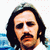 Pixelated static image of a person with long dark hair, mustache, and beard against blue and white background.