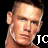 Pixelated close-up of a person's face with short light brown hair, visible ear, and partial shoulder against black background.