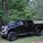 A pixelated image shows a dark vehicle on grass with green foliage in the background, appearing as a low-resolution static icon.