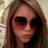 Pixelated close-up of a person with long brown hair wearing dark sunglasses against a light background.