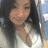 A pixelated close-up of a person with long dark hair wearing a light-colored top against a blurred background.