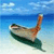 Pixelated image of a small boat on water with a blue sky and clouds, featuring a green hull, brown mast, and light-colored deck.