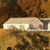 A static pixelated image shows a light-colored building with a sloped roof and white trim against a brownish background.