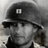 Static grayscale buddy icon of a person wearing a helmet with a small square emblem on the front, viewed from an angle showing partial face and shoulder.