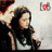 Pixelated image of two figures with dark hair, one in black clothing, against a light background with a small red and gray symbol in the top right.