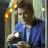A 48x48 pixel animated buddy icon featuring a person in blue clothing holding an object, with green text reading "Original Icons .com" on the right side against a dark background.