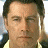 A pixelated image of a man with short dark hair and light skin, wearing a yellow shirt under a dark jacket.