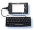 A computer setup with a monitor displaying a blue lowercase 'e' on a white screen, connected to a black keyboard with a coiled cable.