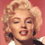 Static pixel art of a woman with blonde curly hair, closed eyes, red lips, and dark earrings against a pink background.