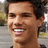 Pixelated close-up of a smiling person with short dark hair, visible teeth, and light skin tone against blurred background.
