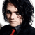 Static pixelated image of a person with long dark hair wearing a black shirt and red tie against white background.