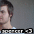 Pixelated image of a person with short dark hair in profile view, wearing a light-colored top against a gray background with text overlay reading "spencer <3".