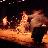Pixelated static image of a figure in motion with warm lighting and dark background, likely representing a performer or dancer on stage.
