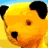 Yellow cartoon bear face with black ears, brown nose, and single visible eye against yellow background with blue sky top.
