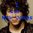 Pixelated image of a person with dark curly hair wearing a black jacket over a white shirt, overlaid with blue text reading "I Luv Nick Jonas".
