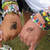 A pixelated image of two hands with colorful beaded bracelets, one hand pointing at a small dark spot on the other hand's palm, set against a green background.