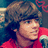 Pixelated image of a person with brown hair in red clothing holding a microphone, overlaid with large white text reading "type your words here" on a blue background.