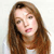 Pixelated image of a person with long brown hair, light skin, and a white top against a light background.