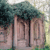 Pixelated image of a stone structure with vertical pillars under a tree, set against a light background with green foliage.