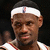 Pixelated close-up of a person wearing a white headband with a small red and blue stripe, dark hair, and a white shirt with red trim.