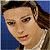 A pixelated image of a person with brown hair and blue eyes, wearing a white top against a blue background on the left side; green text reading "Original Icons .com" appears on a dark green background on the right.