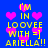 Blue background with yellow text reading 'I'M IN LOOVE WITH =] ARIELLA!!' and pink pixelated hearts scattered throughout.