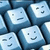 Pixelated static image of four light blue square icons with dark blue borders, each featuring a simple smiling face expression.