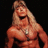 Pixelated image of a muscular person with long blonde hair, open mouth, and visible chest jewelry against black background.
