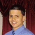 Static pixelated image of a person with short dark hair wearing a light blue shirt against a dark red background.