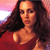 A pixelated portrait of a person with long dark hair wearing a red top against a pink and white gradient background.