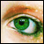 A pixelated close-up of a human eye with green iris, brown eyelashes, and light skin tones against a beige background.