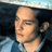 Static 48x48 pixel icon showing a close-up of a person's face with dark hair and light skin, wearing a blue garment against a dark background.