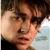 A pixelated close-up of a person's face with dark hair, light skin, and a neutral expression against a blurred background.