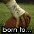A pixelated image of four hands with white wristbands on a grassy background, displaying text overlays.